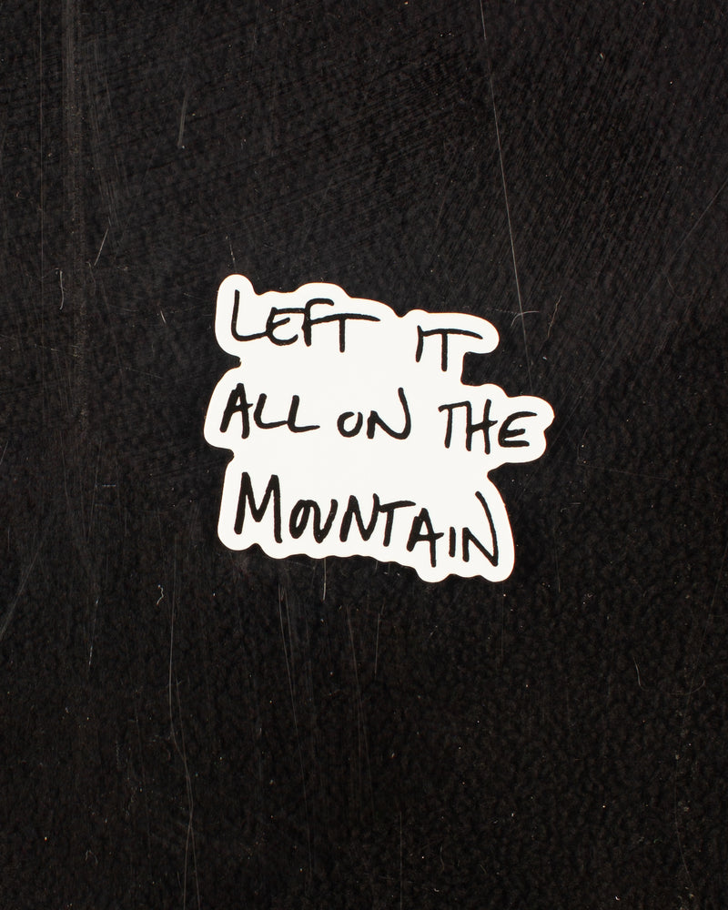 Handwritten sticker in black that reads "left it all on the mountain" with a white background.